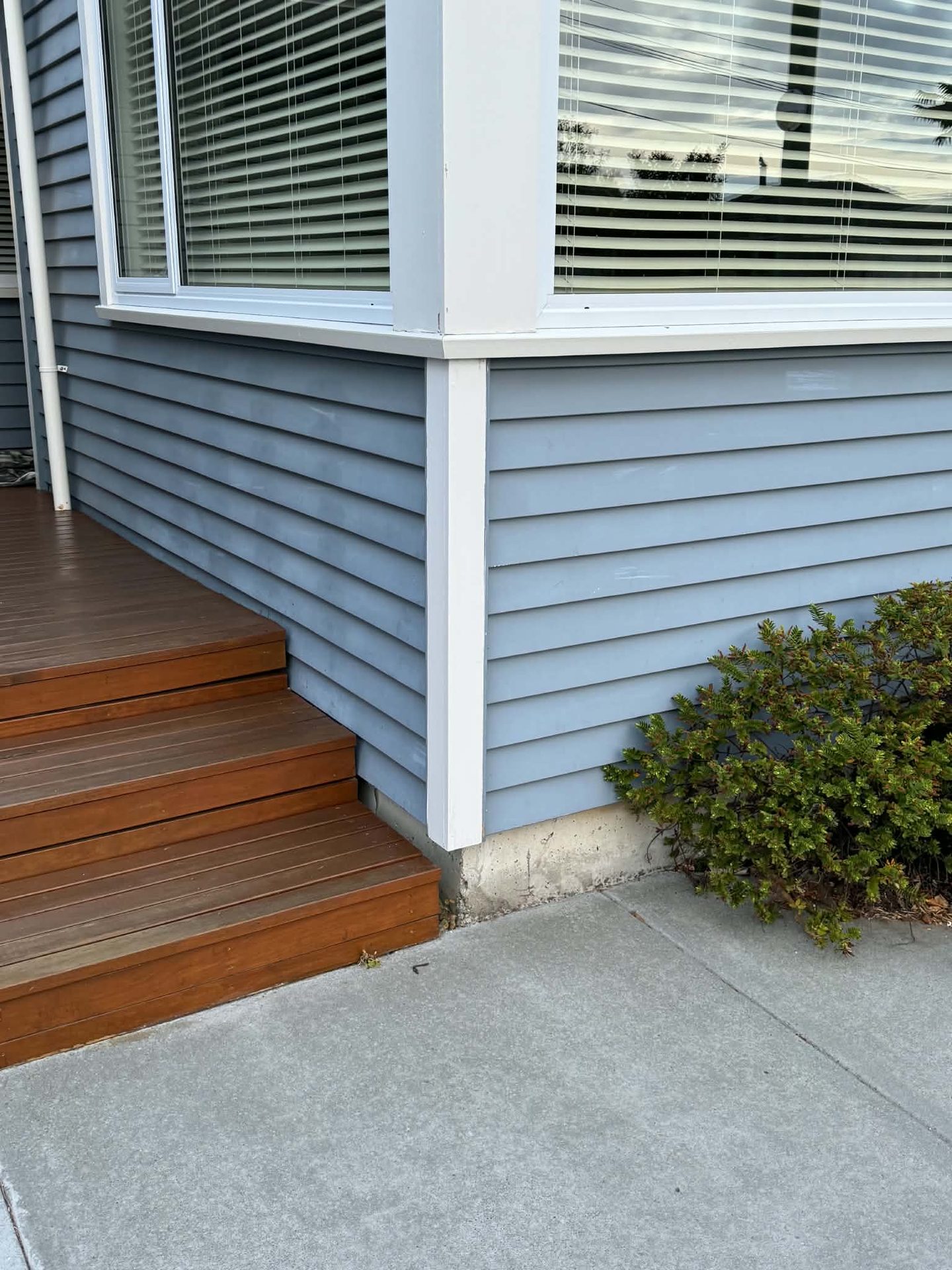 Blue-grey weatherboard exterior corner with a freshly finished timber step