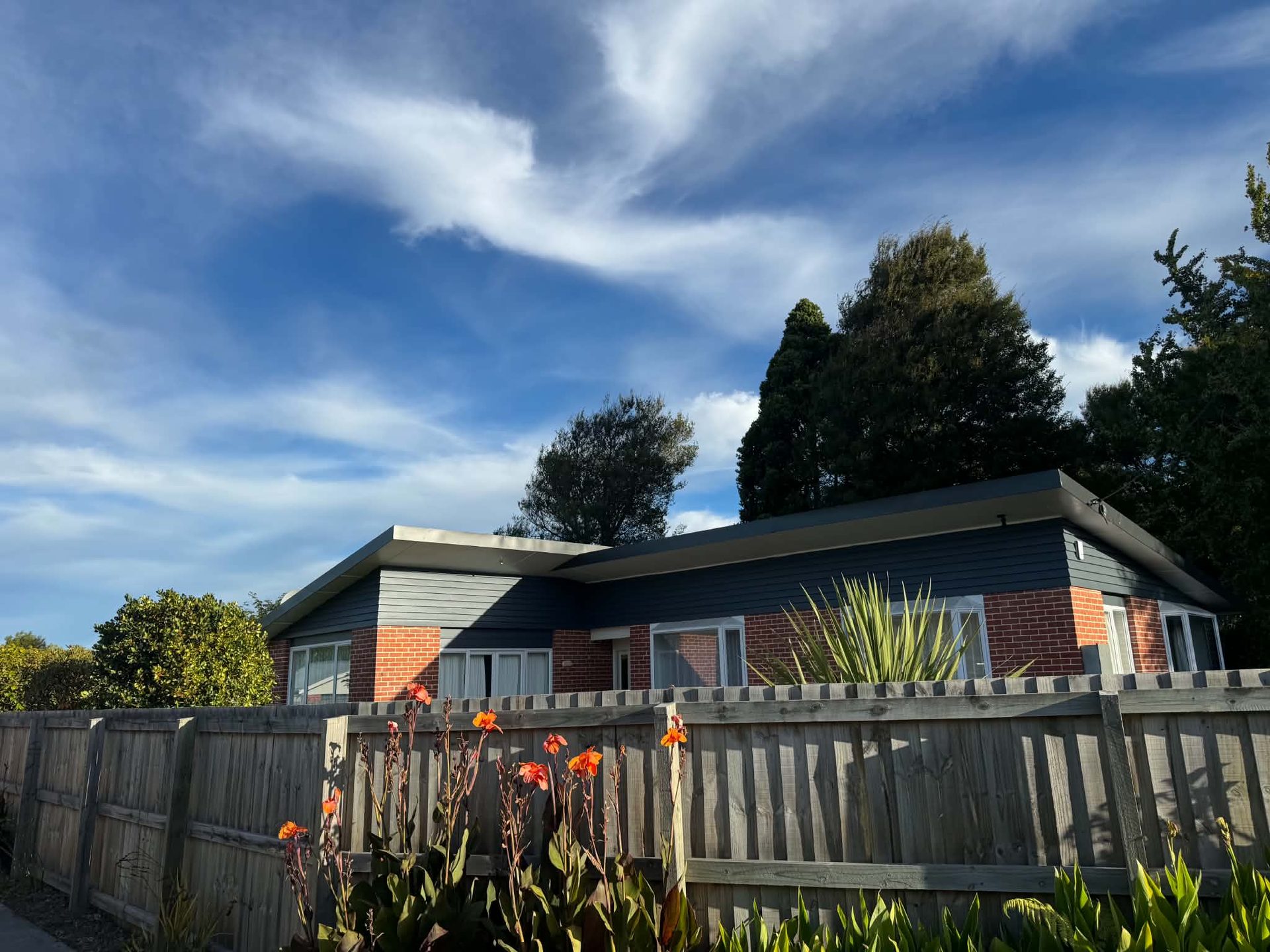 Repainted blue-grey weatherboard house exterior with a tidy fenced garden