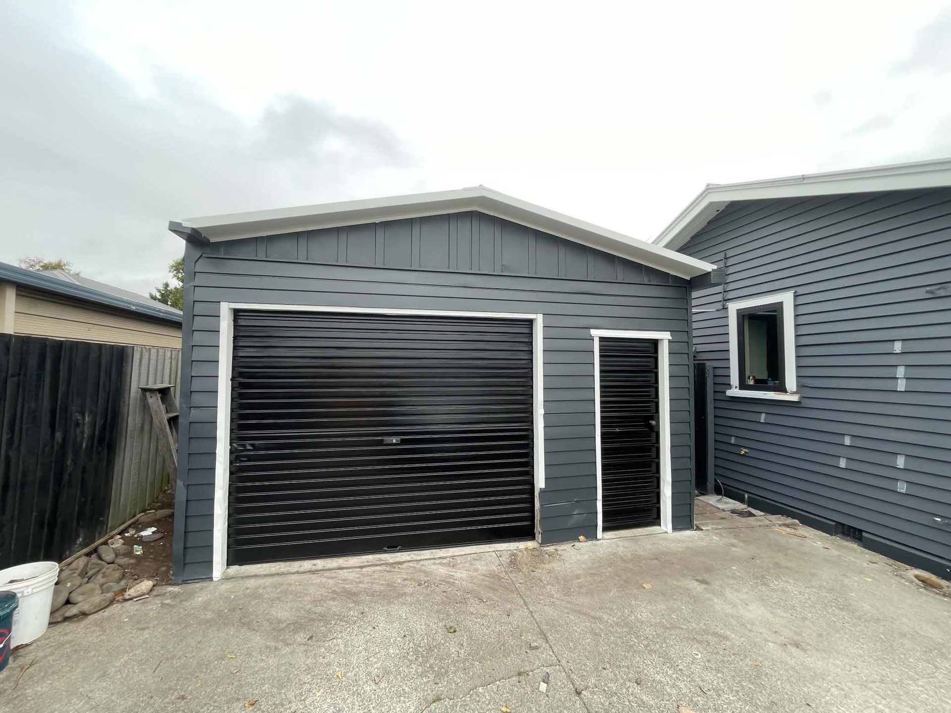 Grey weatherboard home with a matching garage and sealed driveway
