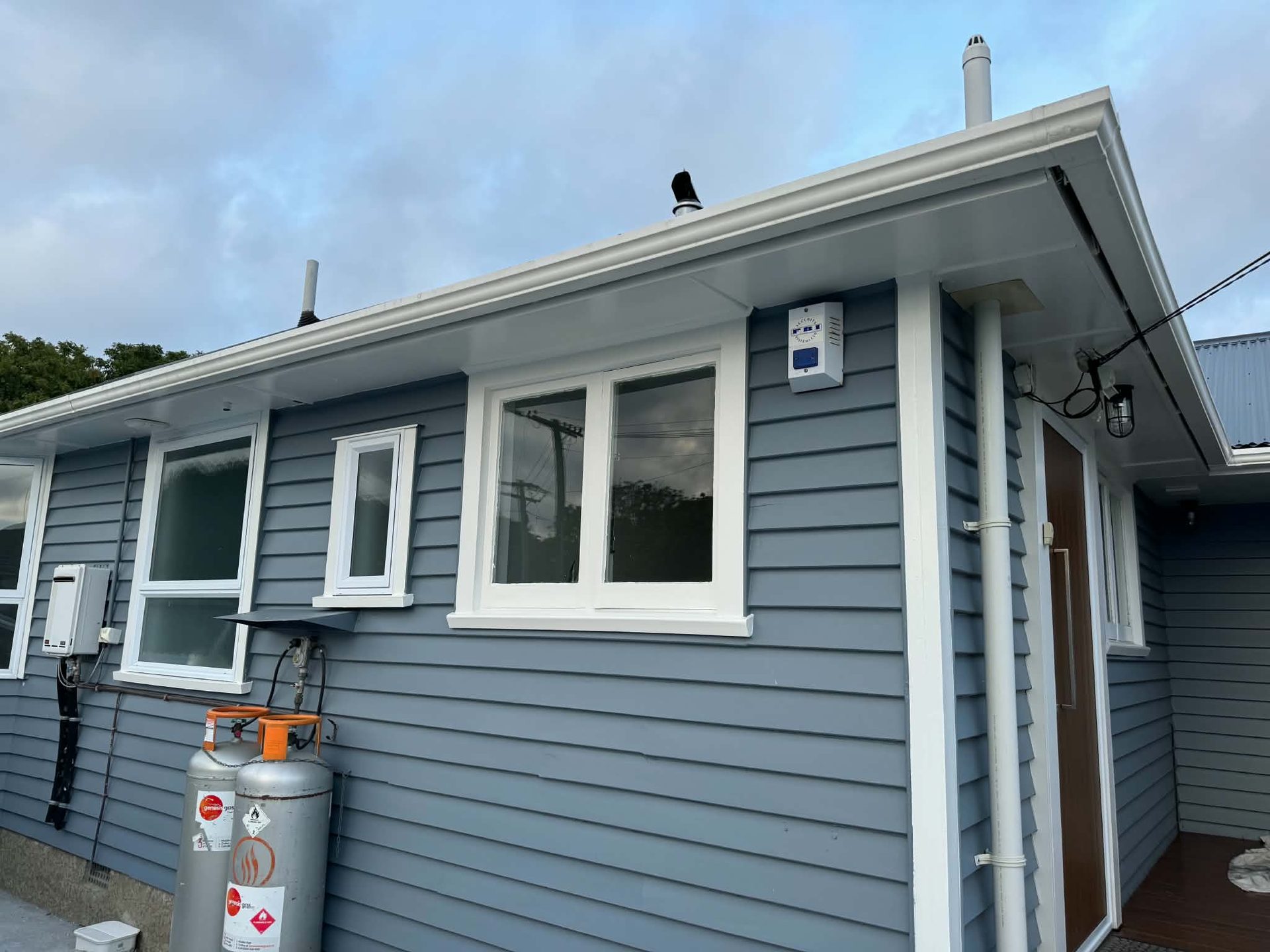 Blue-grey weatherboard facade with white-trimmed windows freshly painted