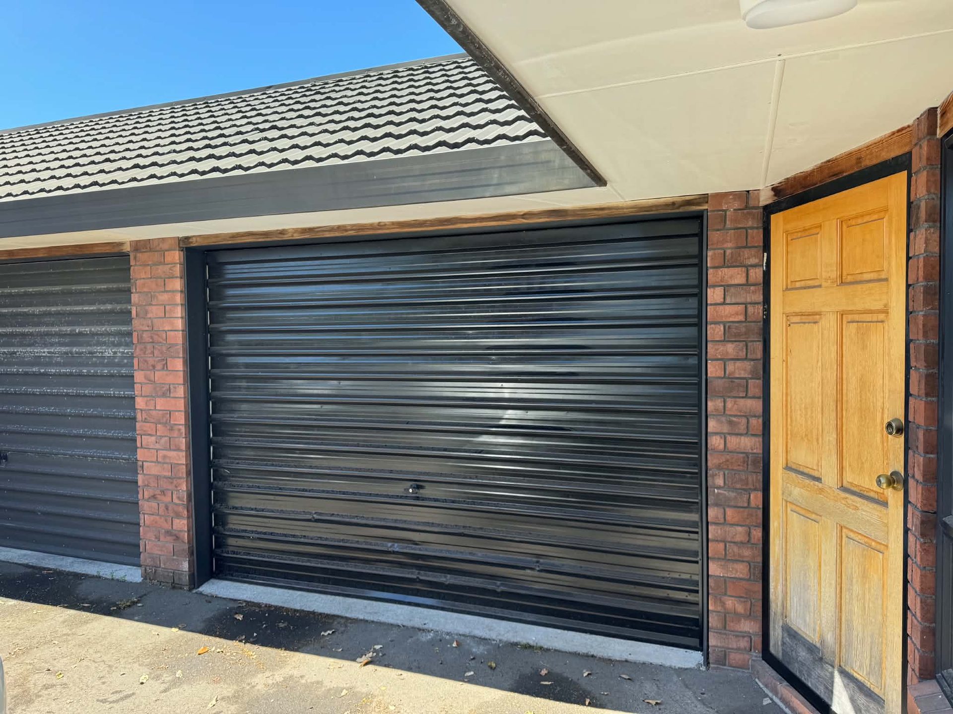 Roller garage door and brickwork beside a repainted timber entry door